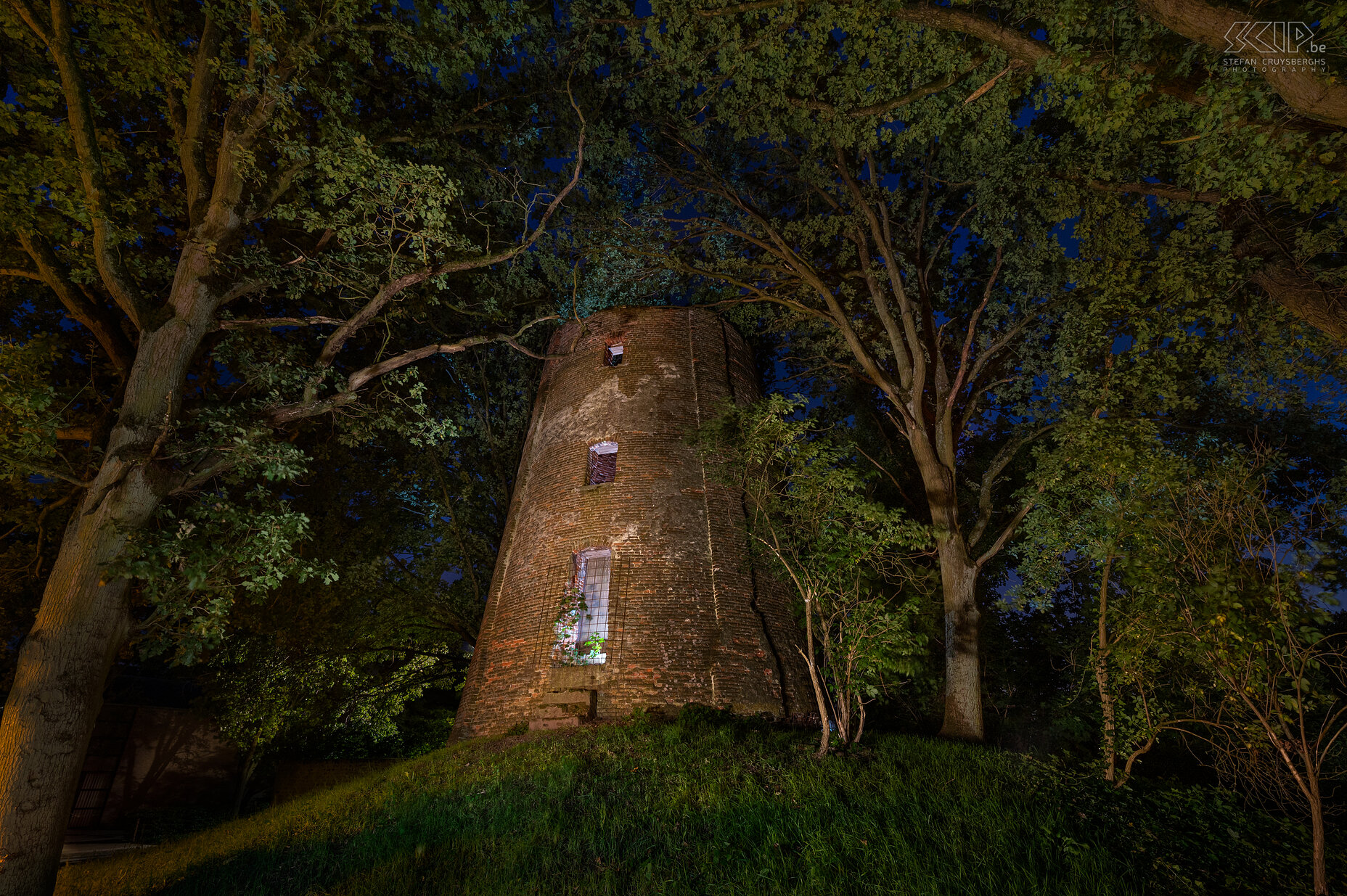 Hageland by night - Mill in Engsbergsen in Tessenderlo The mill in Engsbergsen in Tessenderlo was a grain mill that was built in 1826. The mill has not been in use since 1934 and is now a ruin that stands among the trees in a residential area. The windmill is no longer photogenic at all and yet I tried to make a few atmospheric images of it in the evening with a few flashes and LED lamps. Stefan Cruysberghs